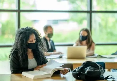 three masked students studying